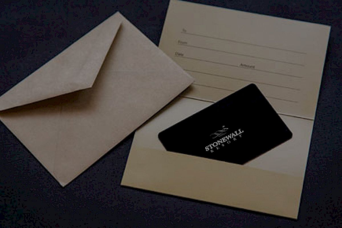 The image shows an open envelope next to a cardholder containing a black card. The cardholder has fields for name, date, and amount.